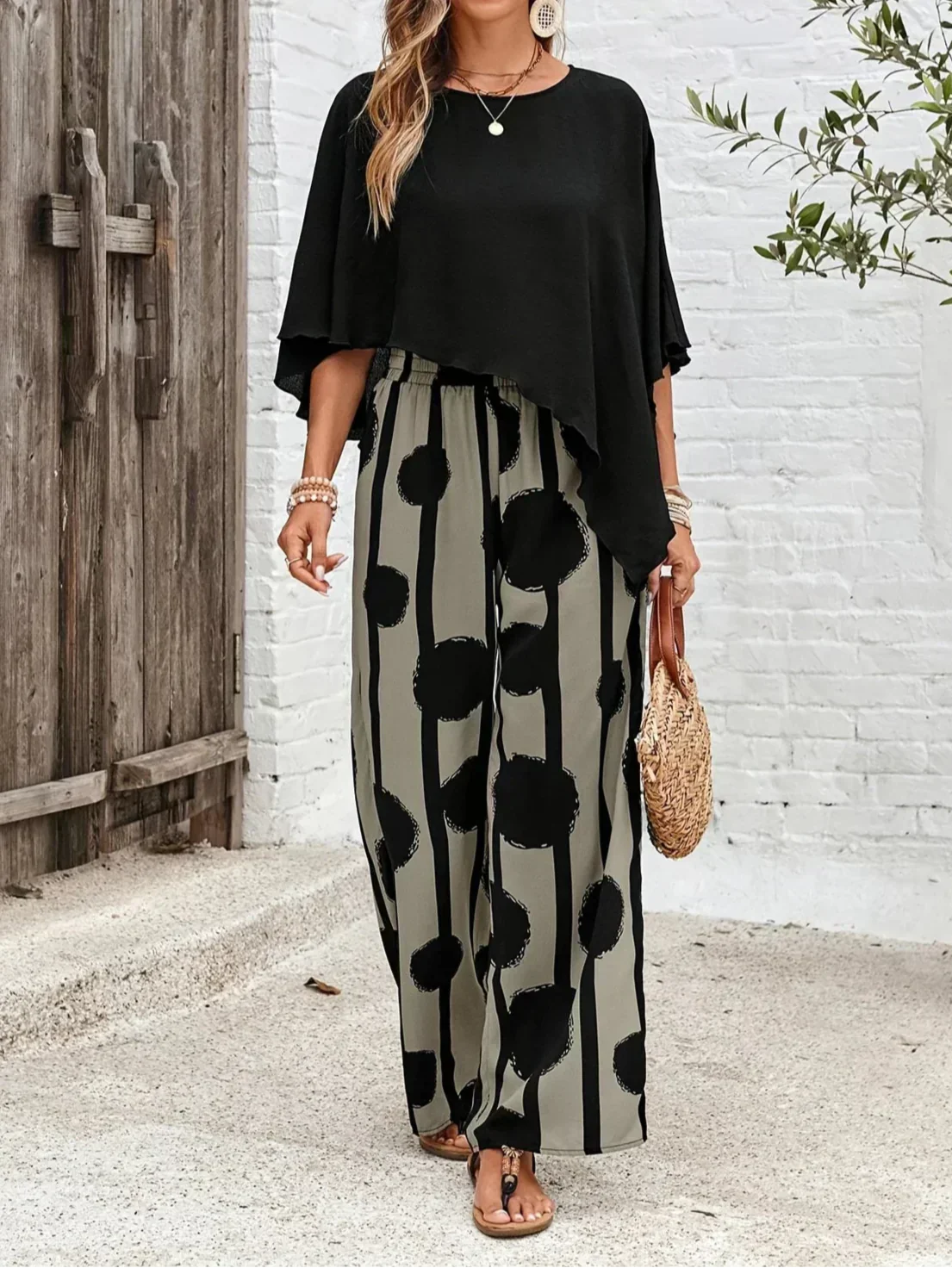 Black asymmetrical blouse with loose sleeves and wide-leg boho pants featuring black dot print