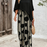 Black asymmetrical blouse with loose sleeves and wide-leg boho pants featuring black dot print
