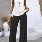 White sleeveless tiered top with black palazzo pants, standing close-up