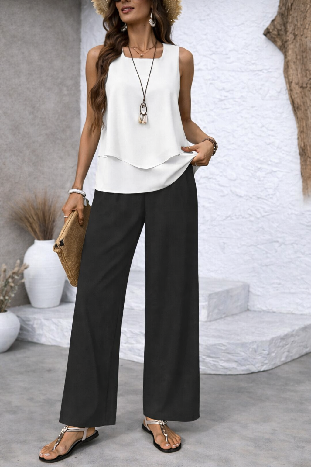 White sleeveless tiered top with black palazzo pants, standing close-up