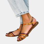 Gold open-toe flat sandals with multicolored ankle strap, buckle, and cross straps
