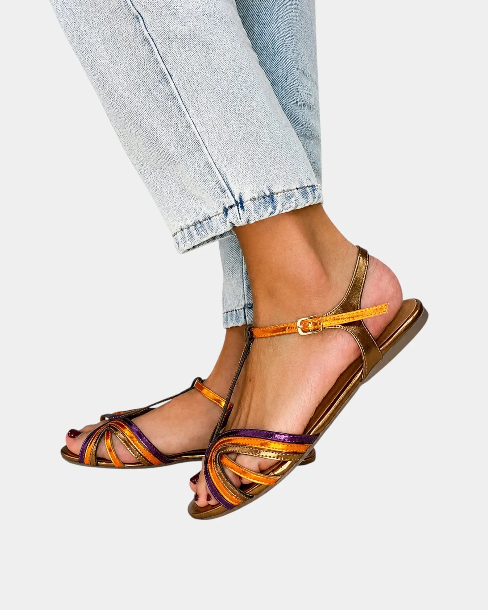 Gold open-toe flat sandals with multicolored ankle strap, buckle, and cross straps