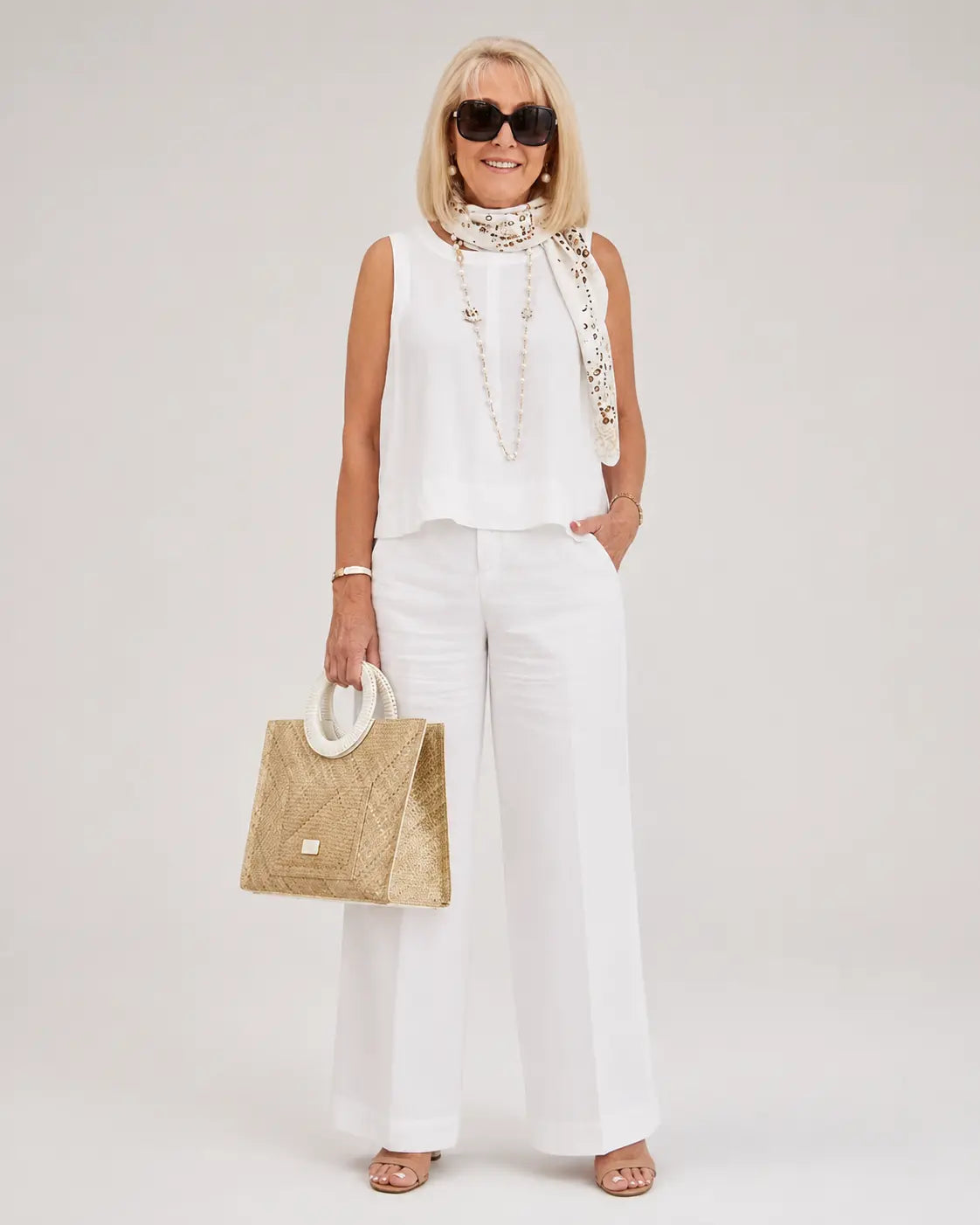 White sleeveless top and wide-leg pants with embellished neck scarf