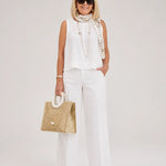 White sleeveless top and wide-leg pants with embellished neck scarf