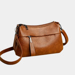 Brown leather shoulder bag with zip-top and adjustable crossbody strap