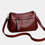 Burgundy leather shoulder bag with zip-top, front pocket, and crossbody strap
