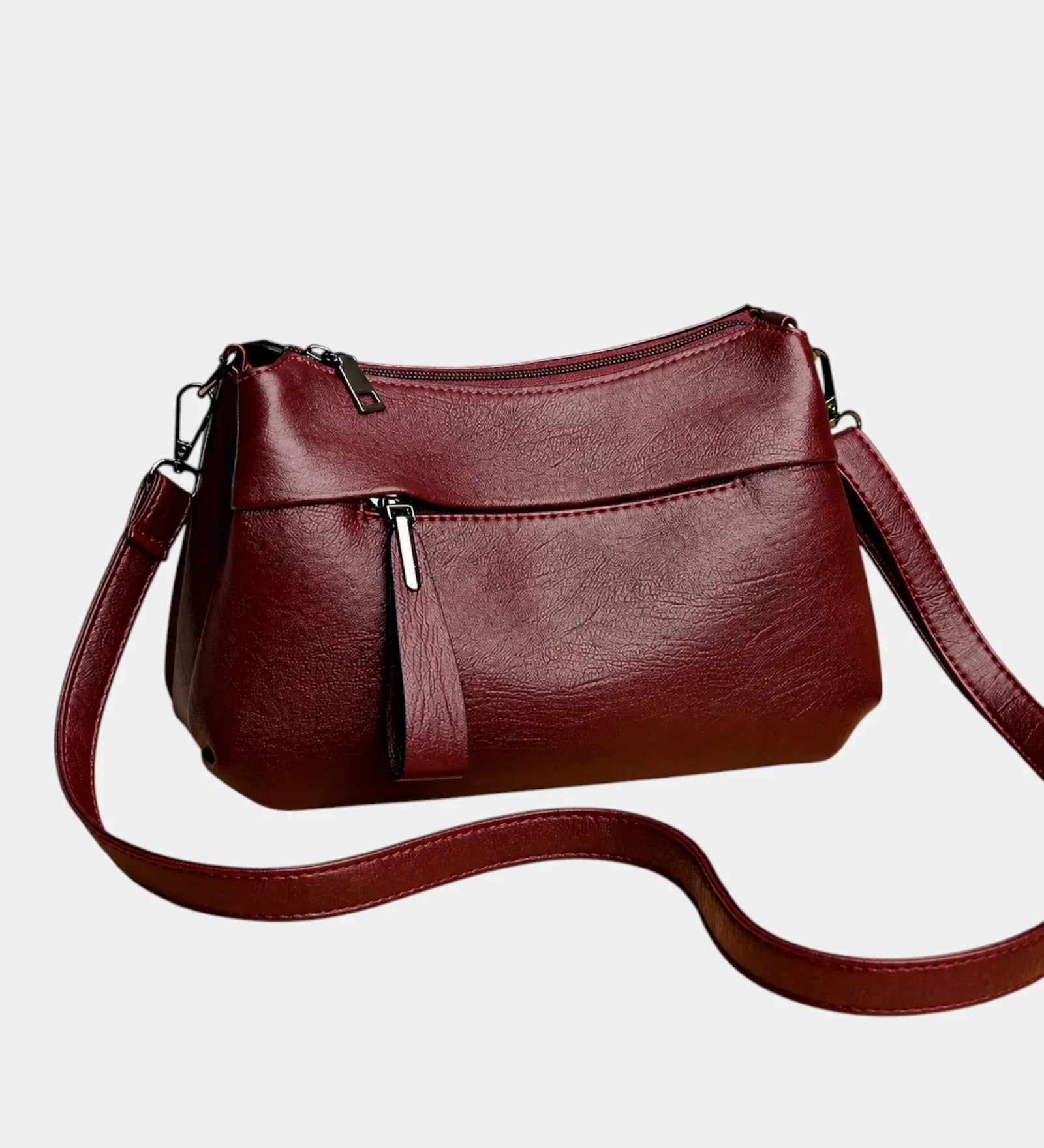 Burgundy leather shoulder bag with zip-top, front pocket, and crossbody strap