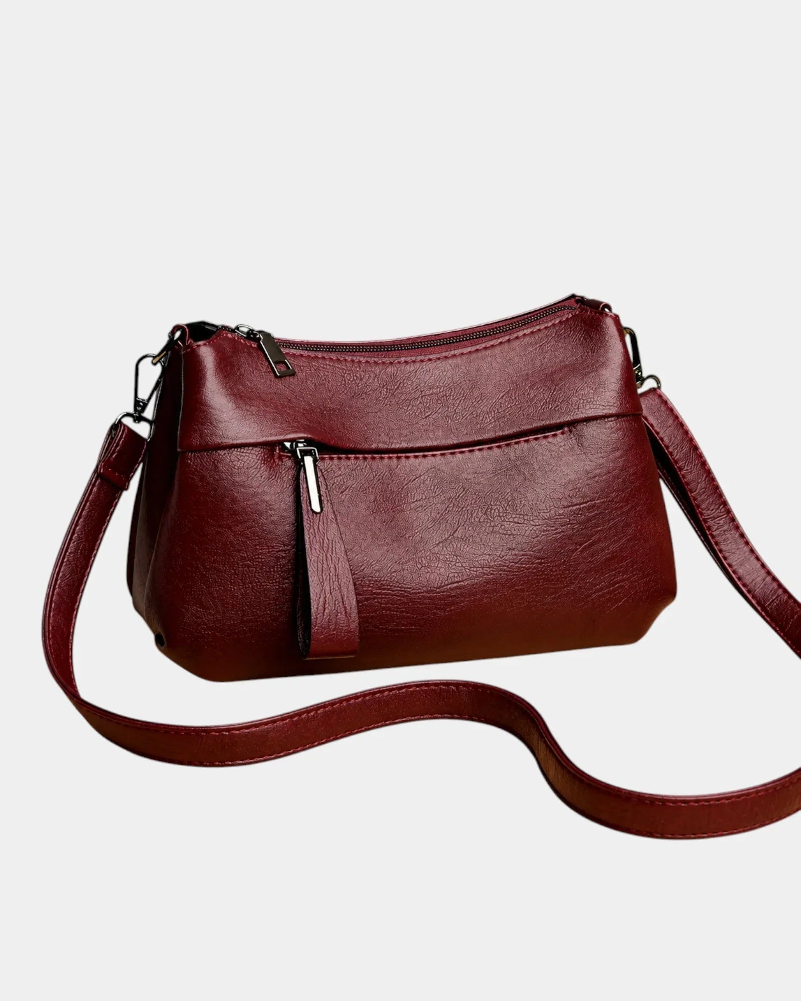 Burgundy leather shoulder bag with zip-top, front pocket, and crossbody strap