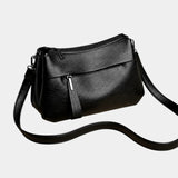 Black leather shoulder bag with zip-top, front pocket, and crossbody strap
