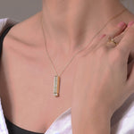 Gold-tone pendant necklace with clear-stone bar charm resting on neckline