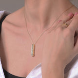 Gold-tone pendant necklace with clear-stone bar charm resting on neckline