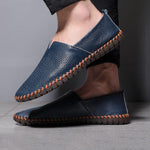 Blue and black leather slip-on espadrilles with orange stitched trim on feet