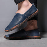 Blue and black leather slip-on espadrilles with orange stitched trim on feet