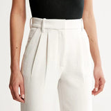 Close-up of light beige/cream trousers waistband with belt loops and pleated front