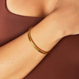 Gold open cuff bracelet worn on wrist