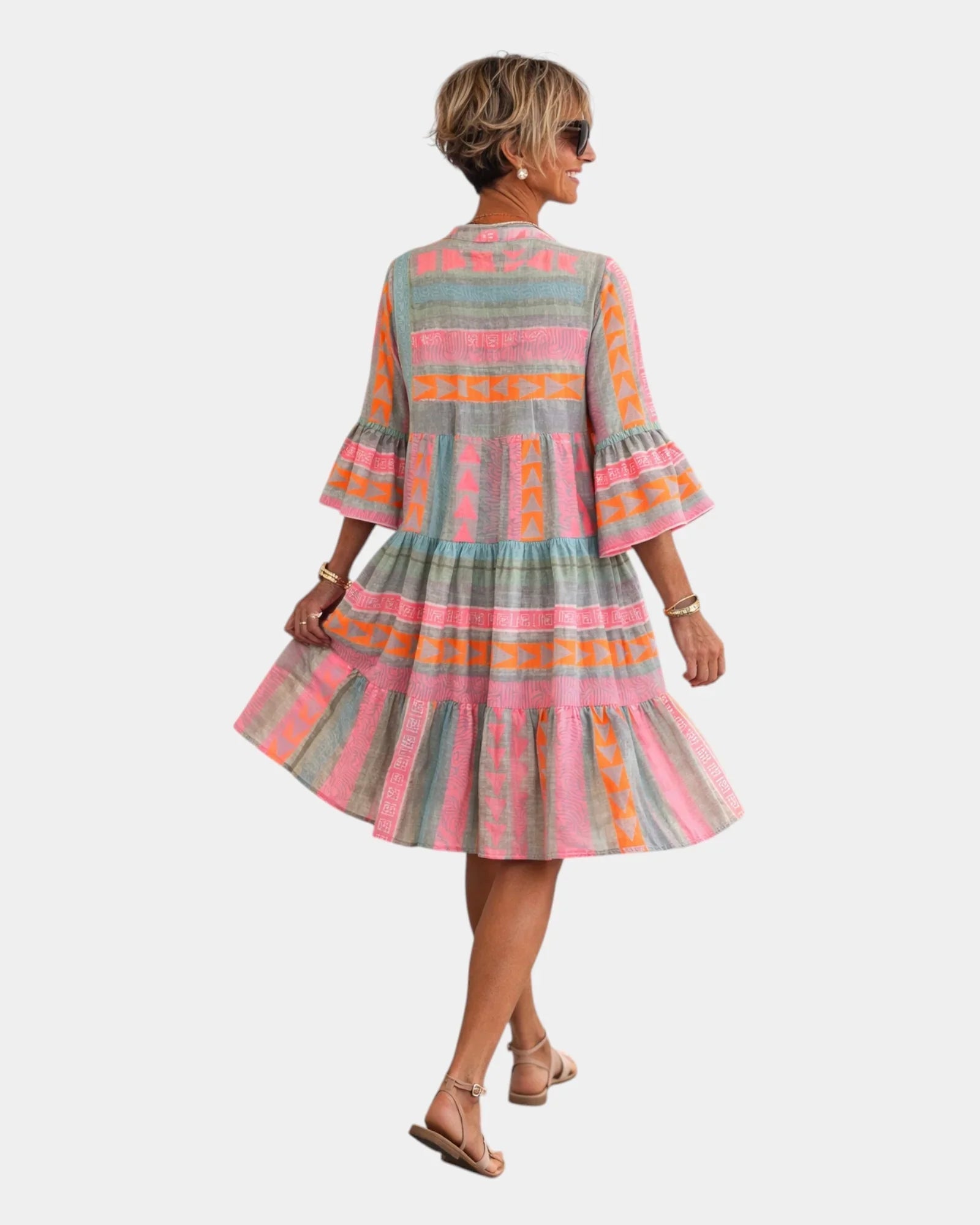 Back view of printed midi dress with tiered skirt and bell sleeves in pink, orange, and greenish