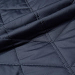Navy quilted jacket fabric close-up with stitched diamond pattern and seam lines
