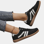 Black orthopedic sneakers with white side stripes and tan gum sole