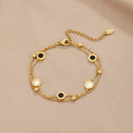 Gold chain bracelet with alternating black and white round stone discs on clasp side