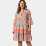Printed midi dress with V-neck and tiered skirt, pink and orange geometric print on greenish fabric
