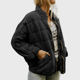 Black oversized quilted jacket with front zipper, stand collar, and patch pockets.
