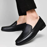 Black leather loafers on feet, slip-on design with low block heel and stitching
