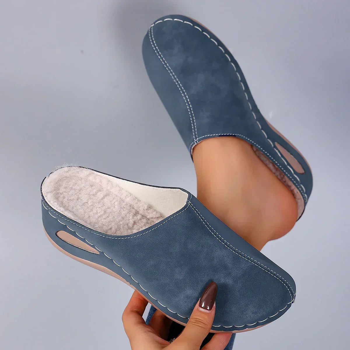 Blue slip-on slippers with cushioned lining and stitched trim, with side cutouts.