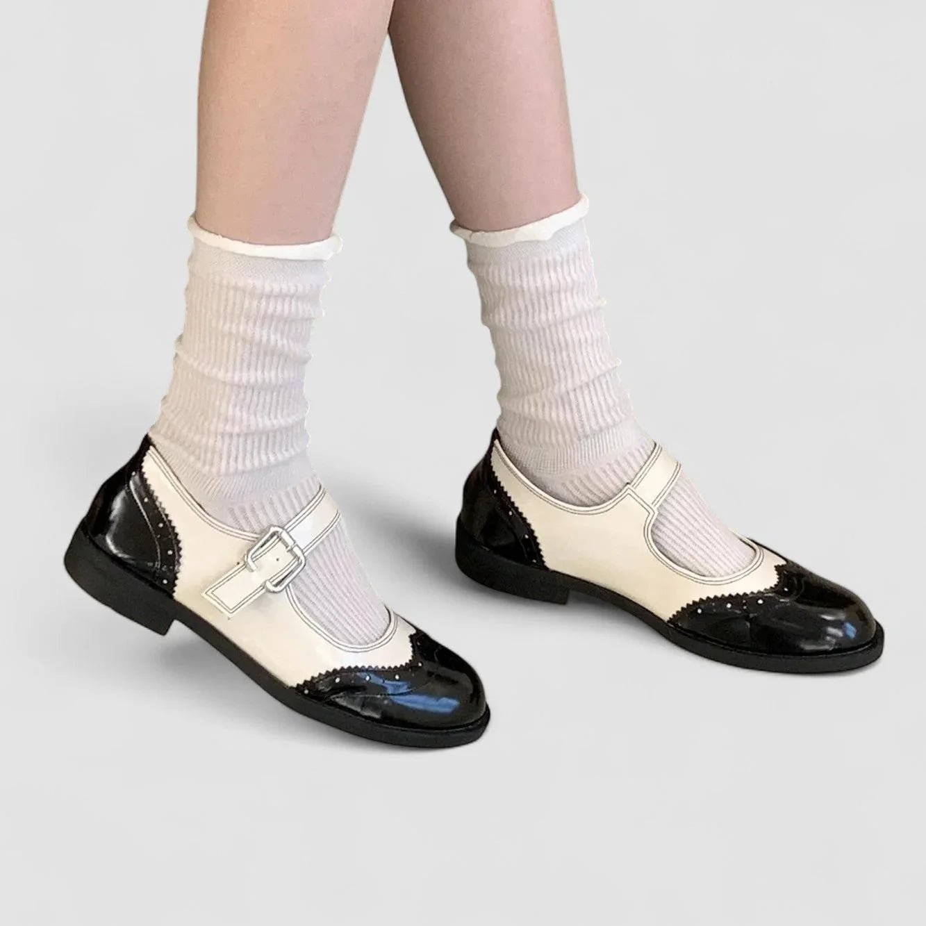 Two-tone classic buckle shoes, black leather with cream strap and scalloped toe trim.