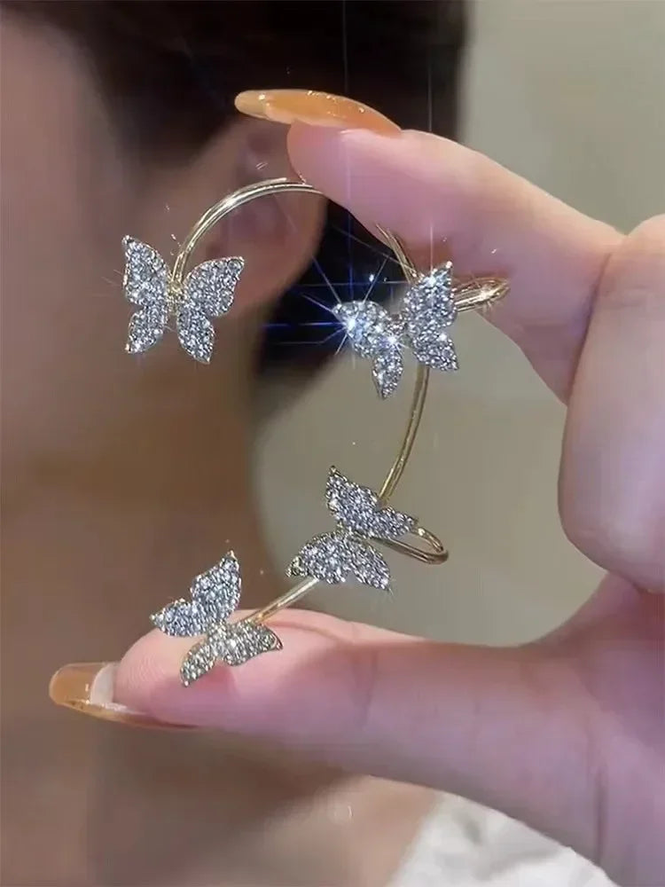 Silver butterfly ear cuff held in hand, four crystal butterflies on open band