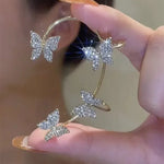 Silver butterfly ear cuff held in hand, four crystal butterflies on open band
