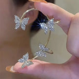 Silver butterfly ear cuff held in hand, four crystal butterflies on open band