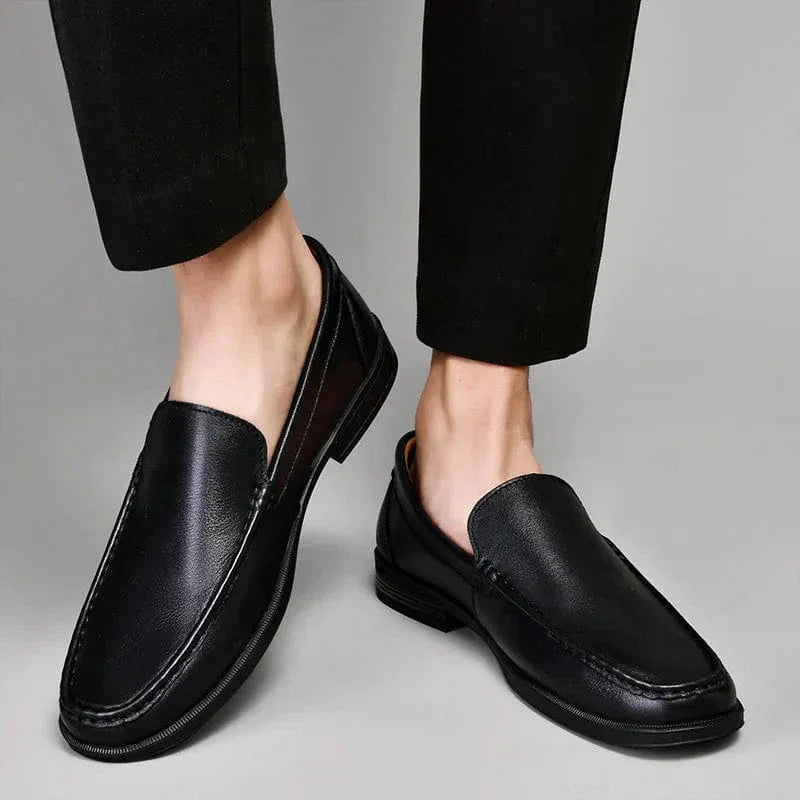 Black leather loafers on feet, side view slip-on with low block heel