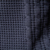 Close-up of dark blue knit sweater fabric with dotted pattern and vertical rib lines