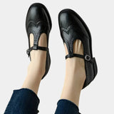 Women's black T-band dress shoes with brogue detailing and buckle ankle strap