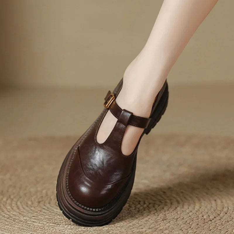Brown T-bar loafers with gold buckle, T-strap cutout, and treaded sole