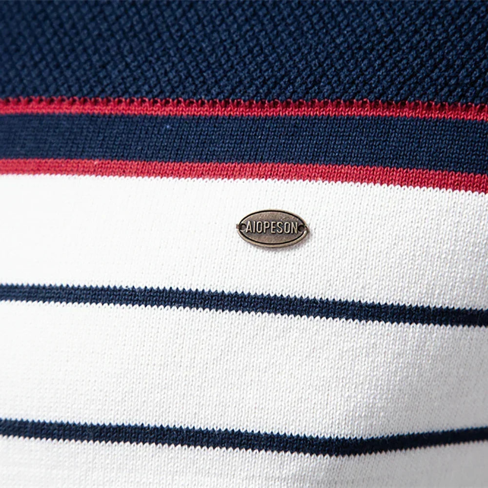 Striped knit sweater close-up with oval brand badge on white fabric, blue and red bands