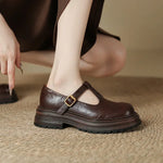 Brown Mary Jane leather shoe on foot, T-strap with gold-tone buckle