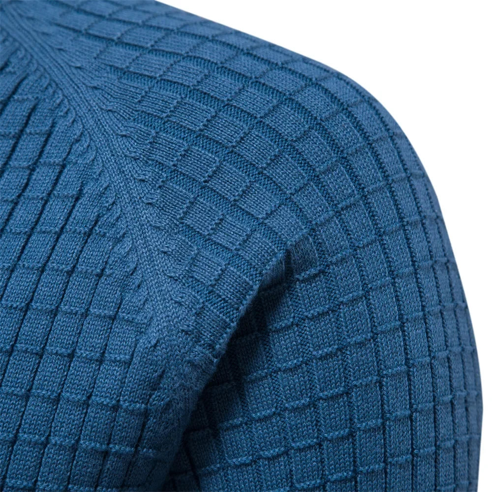 Blue knit sweater fabric close-up with textured grid pattern on sleeve and shoulder.