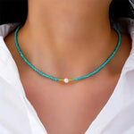 Turquoise beaded pearl necklace with small gold accents and central white pearl