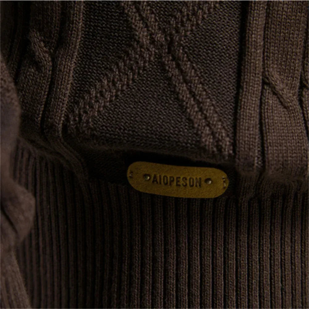 Men's cardigan lower detail in brown with oval brand patch above ribbed hem