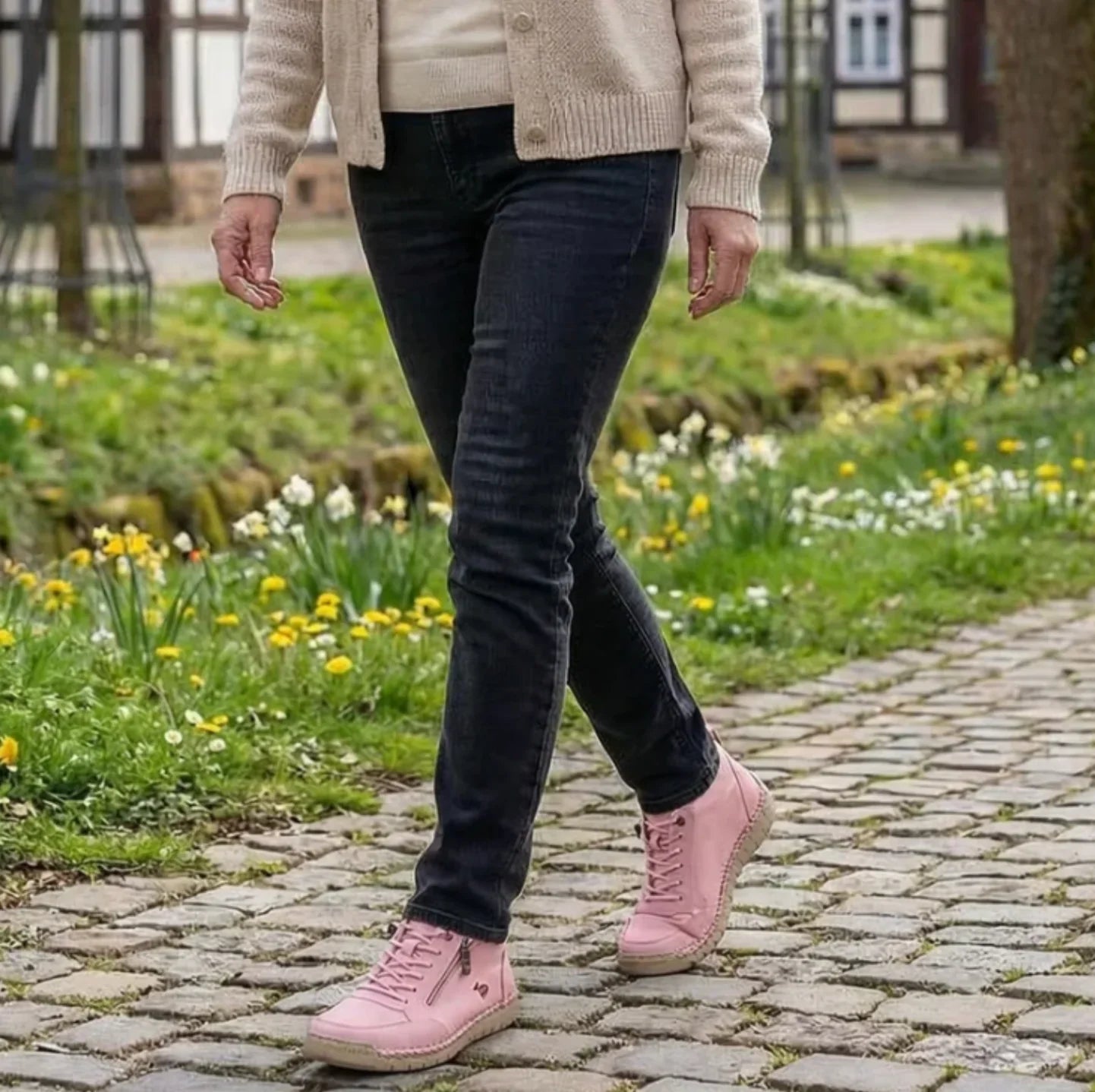Pink lace-up sneakers with side zipper on cobblestone path with pants.