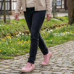 Pink lace-up sneakers with side zipper on cobblestone path with pants.