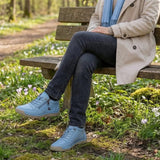 Light blue lace-up sneakers with side zipper worn on outdoor path.