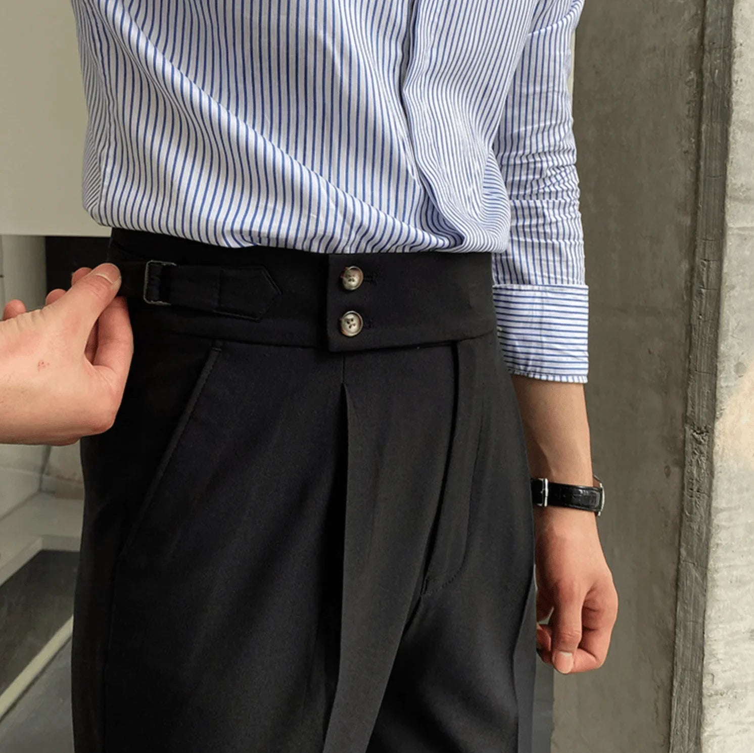 Black high-waisted pants with pleated front, belt loops, and metal button detail