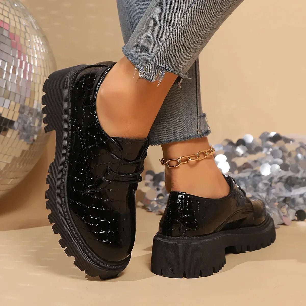 Black patent leather derby shoes with lace-up, rounded toe, and lug sole