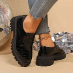 Black patent leather derby shoes with lace-up, rounded toe, and lug sole
