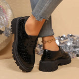 Black patent leather derby shoes with lace-up, rounded toe, and lug sole
