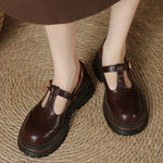 Brown T-bar loafers with gold buckle strap and thick rubber outsole