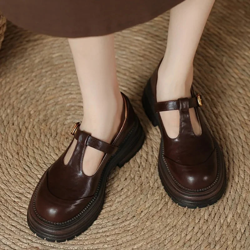 Brown T-bar loafers with gold buckle strap and thick rubber outsole