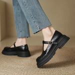 Black leather Mary Jane shoe on foot, T-strap with gold-tone buckle